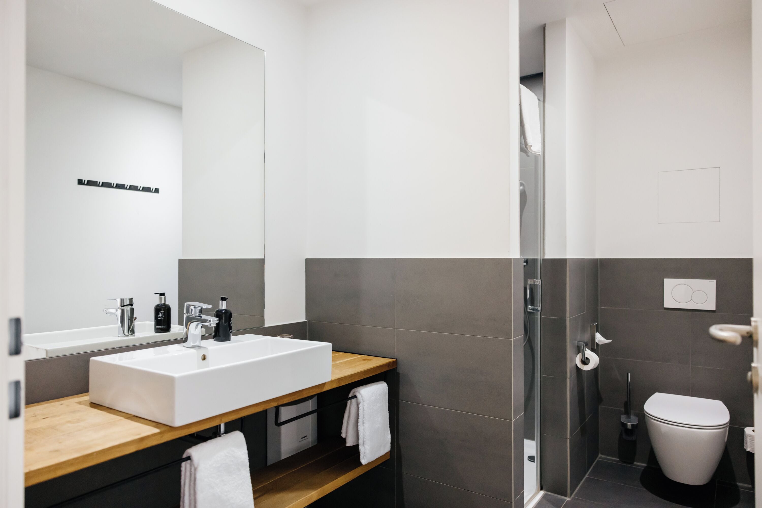 A modern bathroom with a large white sink, wooden countertop, and a glass shower enclosure.