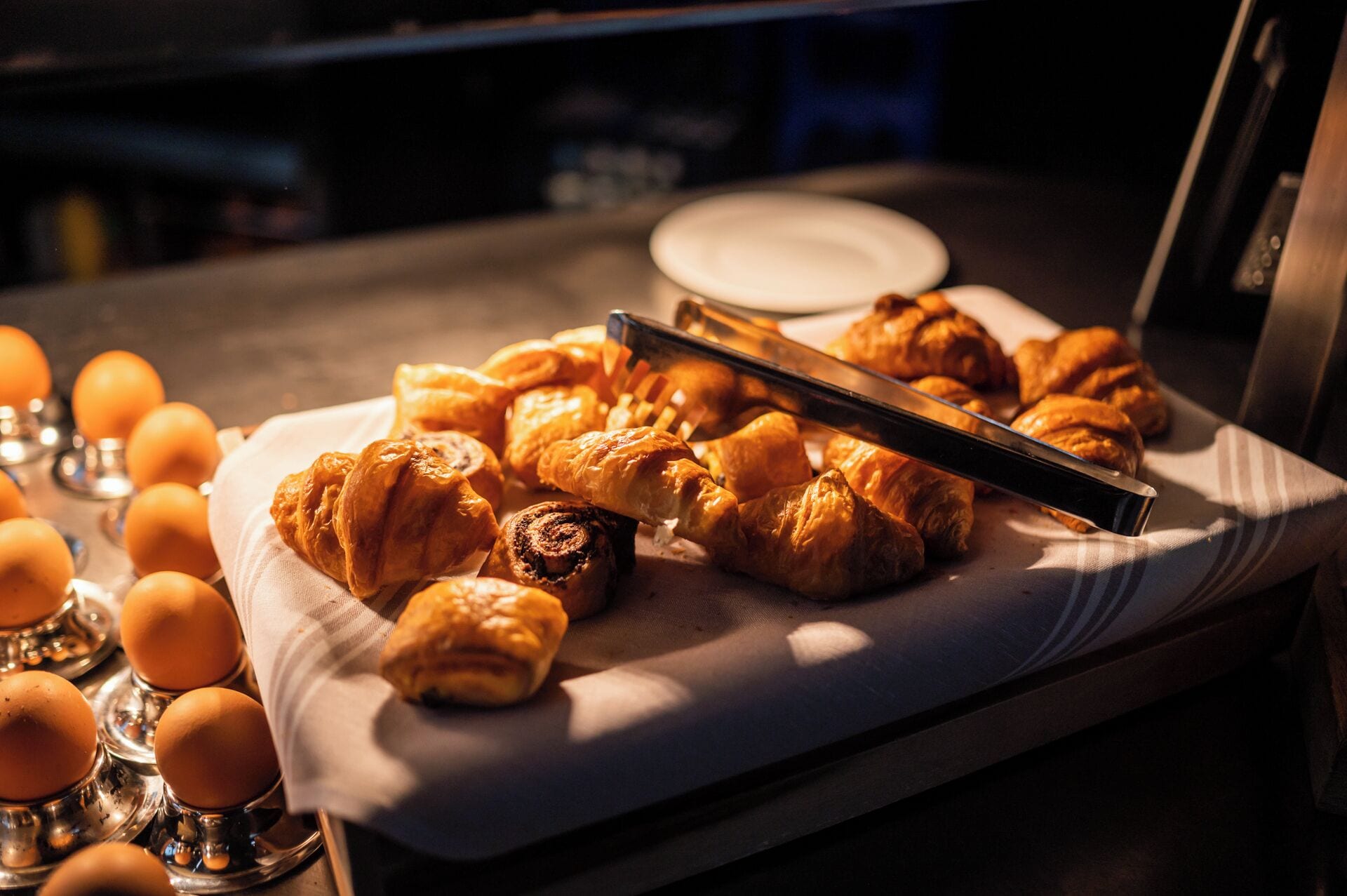 Un plateau rempli de viennoiseries et d’œufs est posé sur une table.