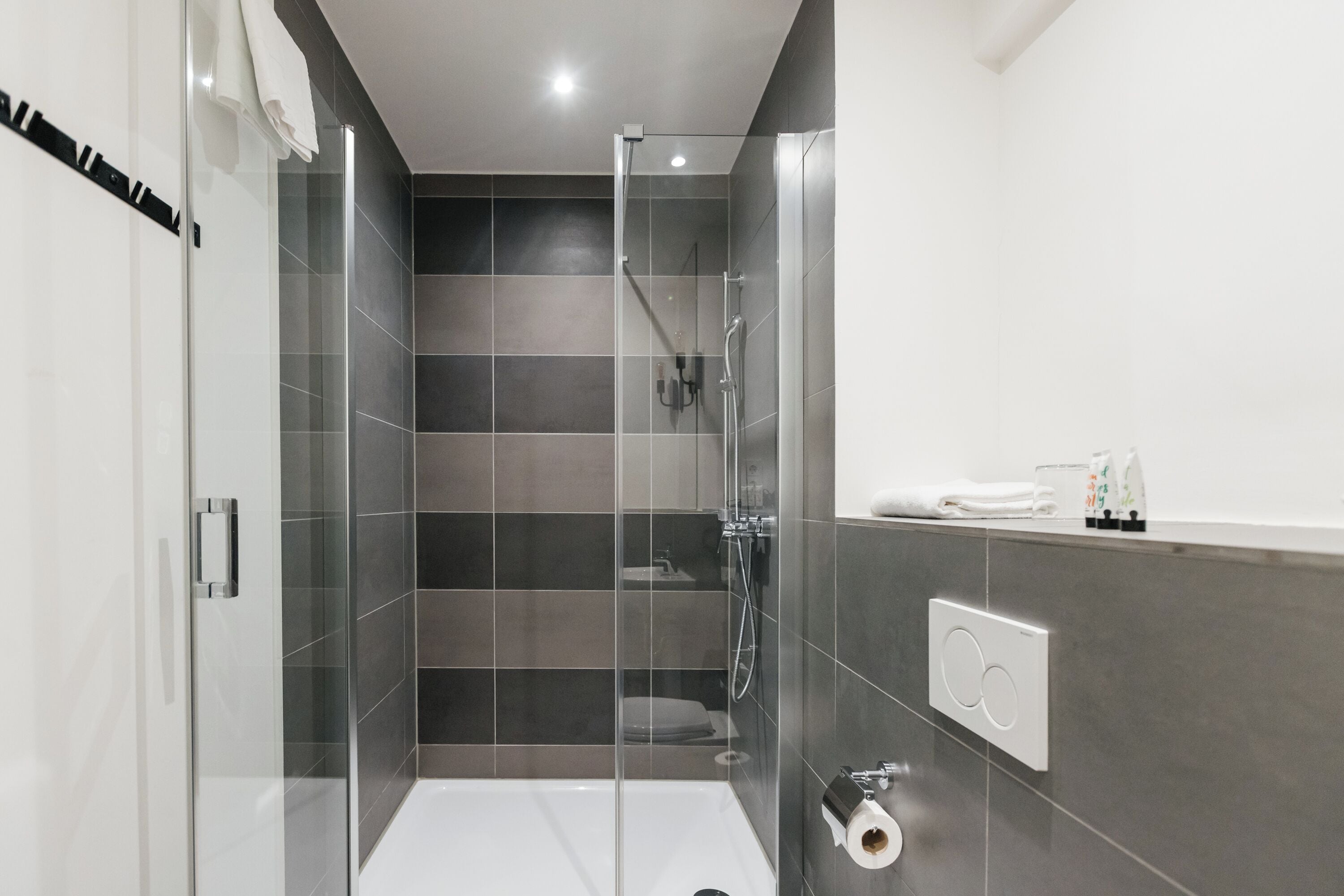 Un baño moderno con ducha envuelta en vidrio, bañera blanca y un perchero para toallas.