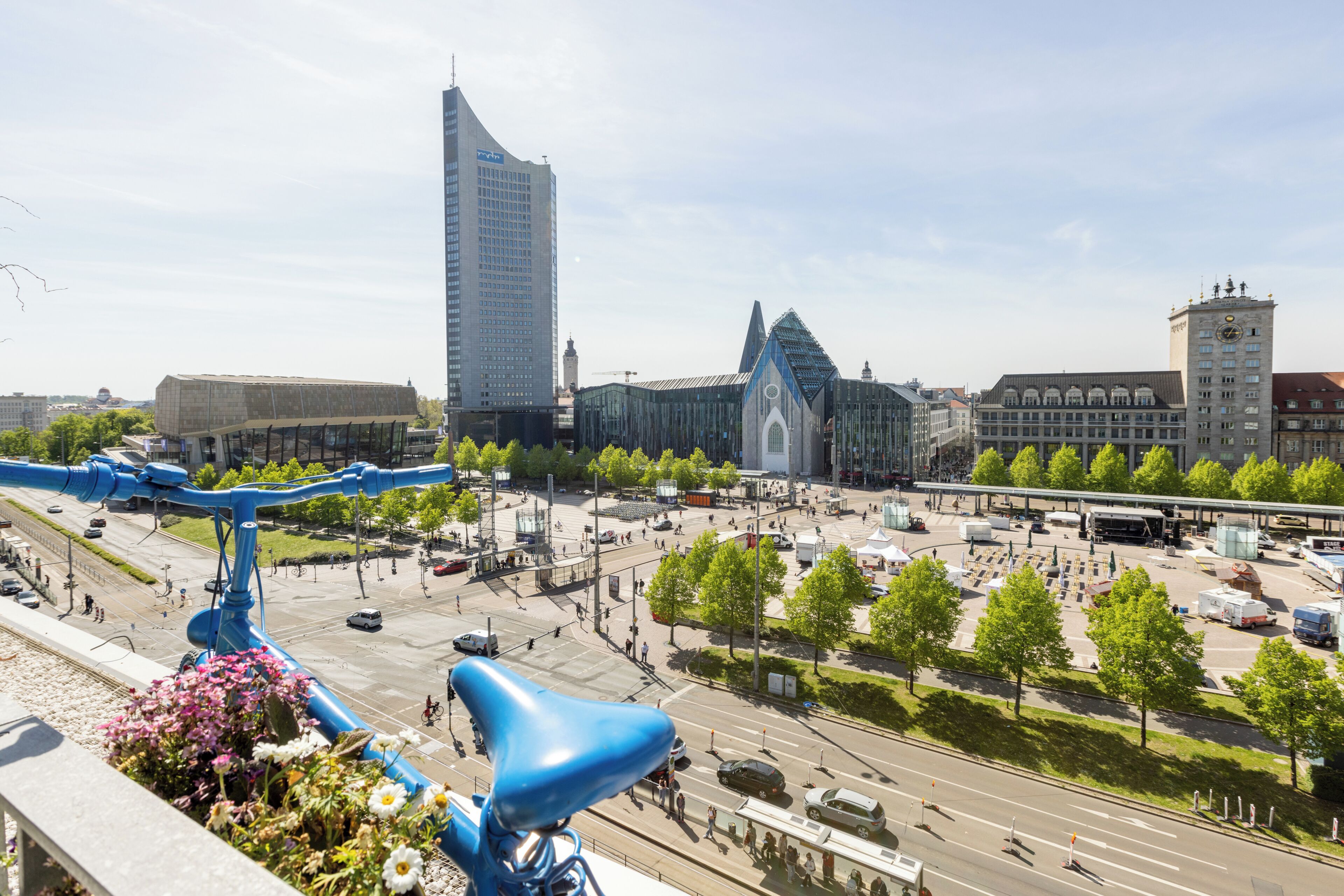 A cityscape with modern buildings, a tram line, and a pedestrian area.