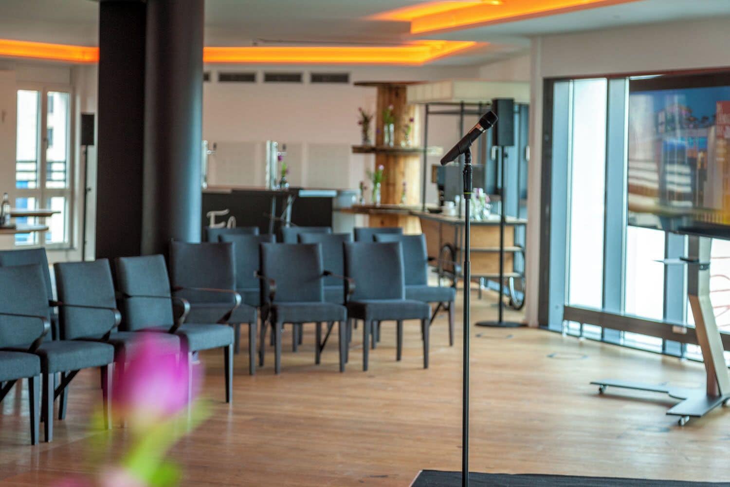 Een moderne congreszaal met rijen stoelen, een spreekgestoelte en een groot raam.