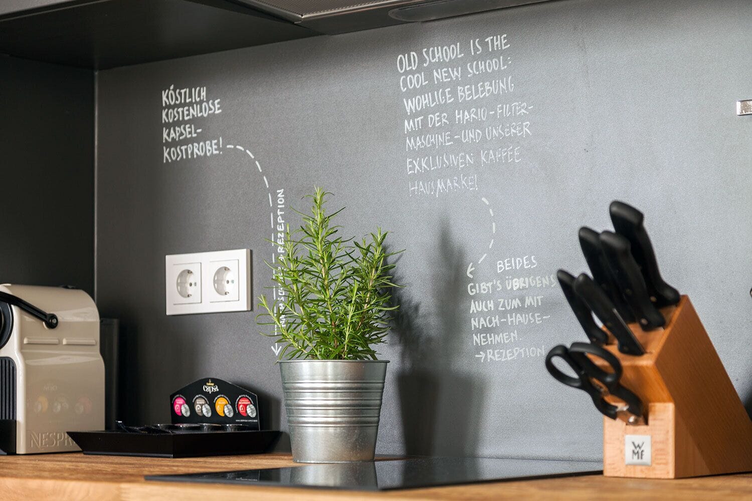 A kitchen area with a coffee machine, a potted plant, and a knife block on the counter.