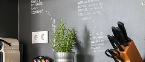 A kitchen area with a coffee machine, a potted plant, and a knife block on the counter.