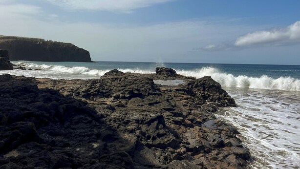 Una costa rocosa con olas rompiendo en la orilla.