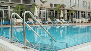 Una piscina con tumbonas y un borde empedrado.