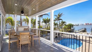 Un espace extérieur abrité doté d’une piscine, de mobilier en bois et offrant une vue sur l’eau et le panorama urbain.