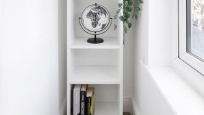 A white bookshelf with shelves containing a globe, a potted plant, and books. - Comfy 4 Bedroom house, Ideal for Workers and Families, FREE Parking (Coulsdon)