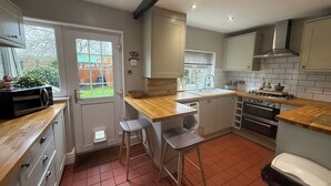 A compact kitchen with a wooden countertop, a built-in oven, a sink, and a window with a view of the backyard. - 2bed Cottage - Trawden - Pet Friendly - Sleeps4 (Colne)