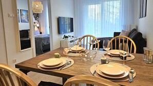A dining area with a wooden table set for four, including plates, cutlery, and glasses. - Apartament Buena Vista - 365PAM (Kolobrzeg)