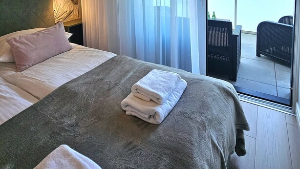 A hotel room with a bed, pillows, and a view of the outside balcony. - Apartament Buena Vista - 365PAM (Kolobrzeg)