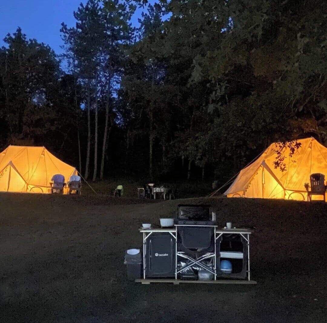 To telte med et campingbord og stole imellem.