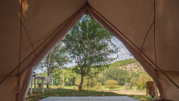 A tent with a view of a tree and hills.