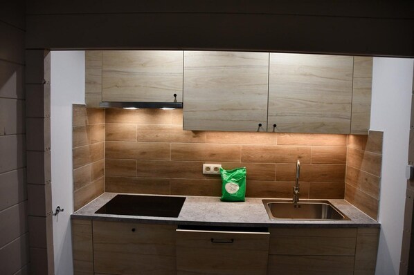 A kitchen with a double sink, wooden cabinets, and a green bag on the countertop. - Modern Chalet in Dochamps With Terrace (Manhay)