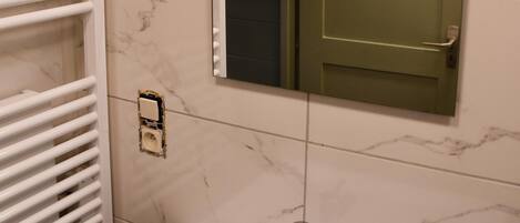 A bathroom with a white sink, a mirror, and a towel rack.