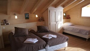 A cozy cabin room with two beds, wooden walls, and a sloped ceiling. - Chalet, wifi, view mountain, terrace, balcony, parking, ski locker, 152m², Le Grand Bornand (Le Grand-Bornand)
