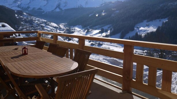 A wooden deck with a table and chairs overlooking a snowy mountain landscape. - Chalet, wifi, view mountain, terrace, balcony, parking, ski locker, 152m², Le Grand Bornand (Le Grand-Bornand)
