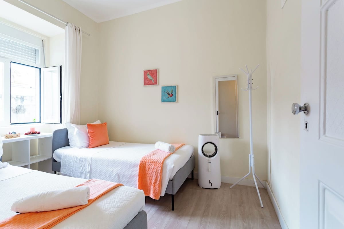 Habitación de hotel con dos camas, un escritorio, un calefactor portátil y obras de arte en la pared.