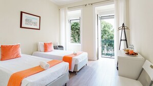 A hotel room with two beds, a balcony, and a small table with a tray of breakfast.