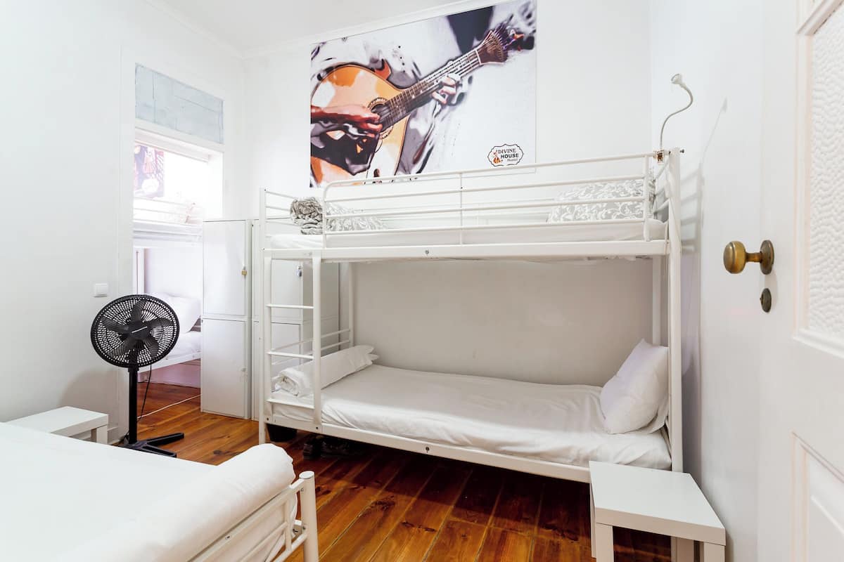 Habitación con literas, un ventilador, una mesita y un cartel en la pared.