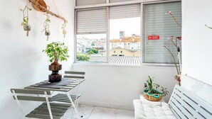 A balcony with a table, chairs, and potted plants.