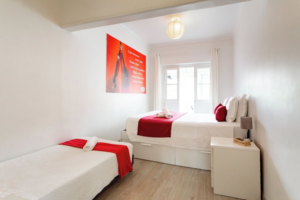 Una habitación con dos camas, una ventana, una lámpara y un cartel en la pared.