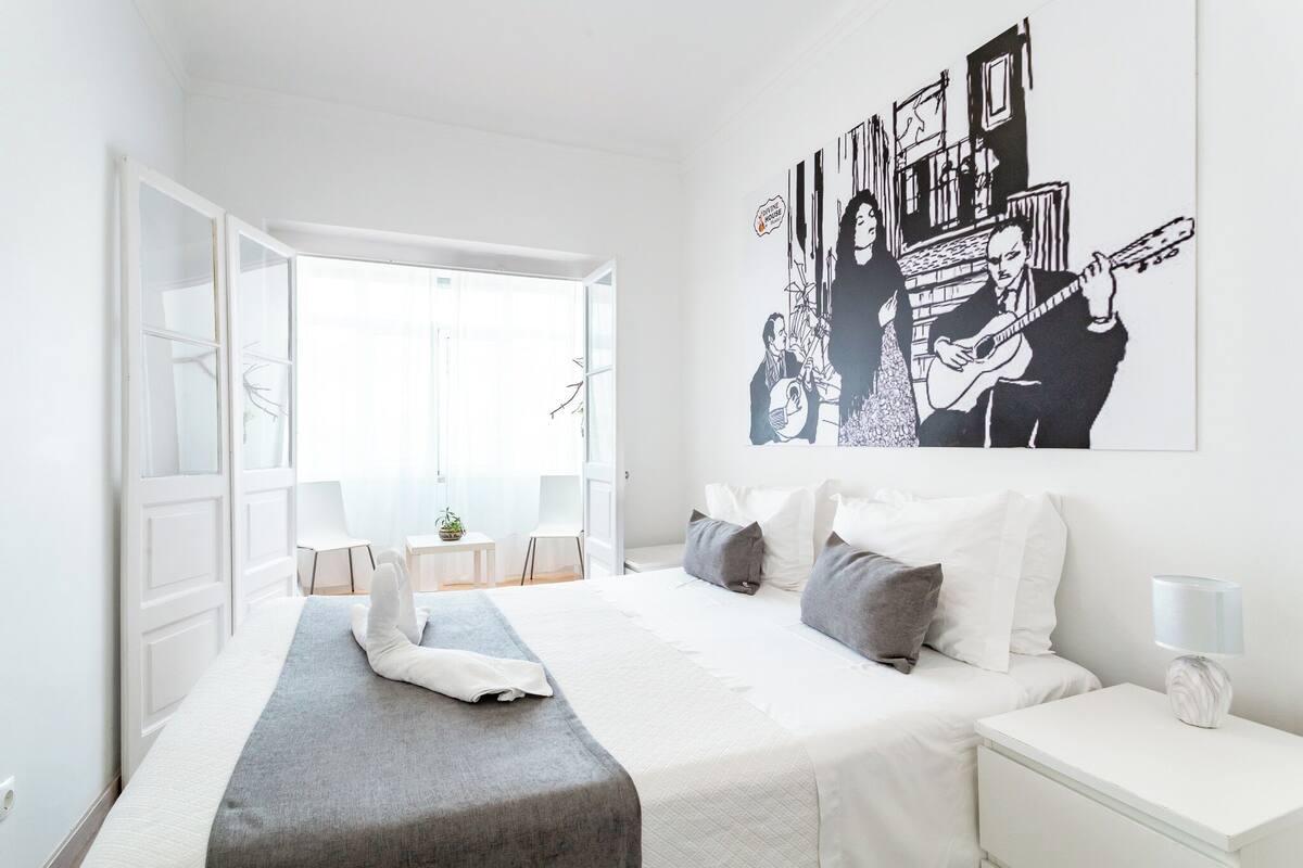 Habitación de hotel moderna con una cama grande, una mesita de noche y un ventanal con vistas.