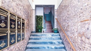 A staircase with marble steps leading to a door, flanked by walls with a speckled pattern and mailboxes on the left.