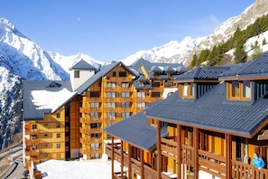 A wooden chalet-style hotel with multiple balconies and a mountain backdrop.