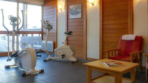 Ett rum med träningsutrustning, en vägg av trä och en röd stol.