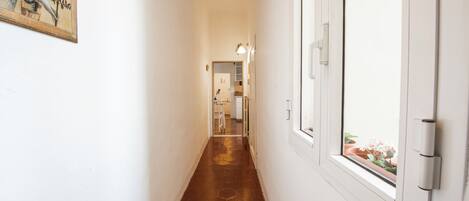 A hallway with a hexagonal patterned floor, white walls, and a door with a window.