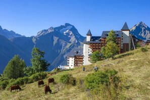Une station de montagne avec des bâtiments de style chalet, un sentier de randonnée et des vaches qui paissent.