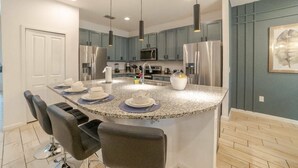 A modern kitchen with granite countertops, stainless steel appliances, and bar seating.