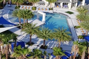 Ein Poolbereich mit Palmen, Liegestühlen und einem Gebäude im Hintergrund.