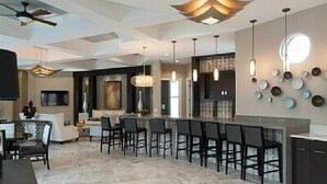 A modern kitchen with a bar area, pendant lighting, and a dining space with chairs.