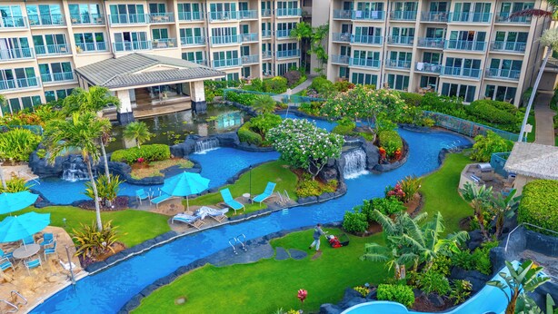 A hotel with multiple swimming pools, lush landscaping, and a large building in the background.