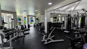 A gym with various exercise machines, dumbbells, and a mirror.