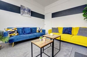 A living room with a blue sofa, a yellow sofa, and a coffee table. - Central - 2br House - Free Parking - Garden (Coventry)