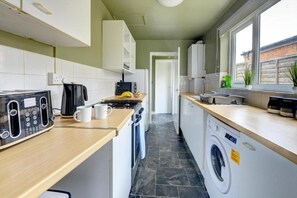 Eine kleine Küche mit einem Toaster, einer Kaffeemaschine und einer Waschmaschine.