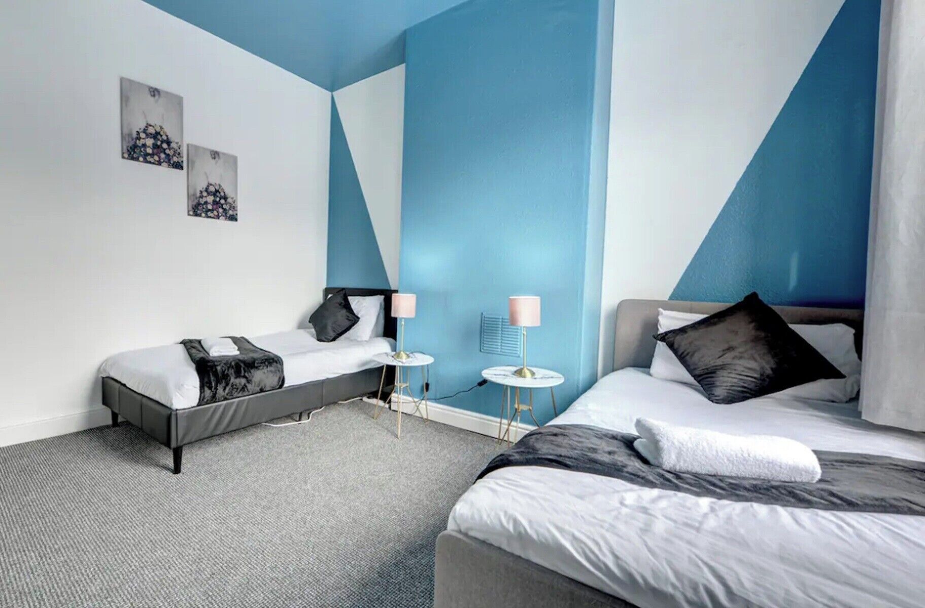 A modern hotel room with two beds, a small table, and a chair.