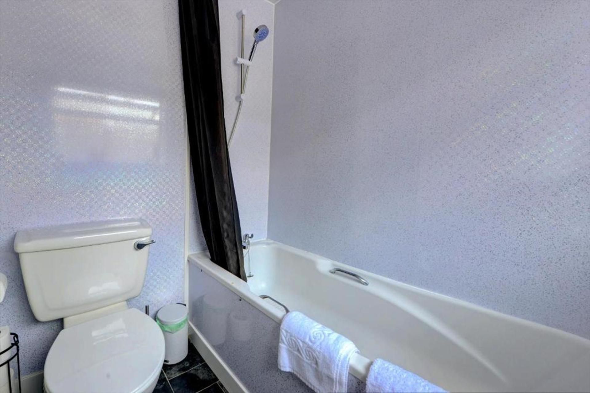 Un baño con inodoro, bañera y zona de ducha.