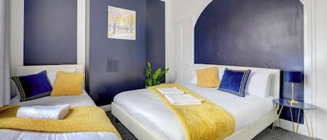 A hotel room with two beds, a large arched window, and a painting on the wall.