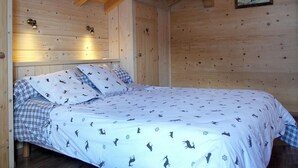 A wooden cabin bedroom with a bed, two bedside lamps, and a framed picture on the wall. - Chalet, wifi, 100m from ski slopes, hammam, terrace, balcony, fireplace or stove, parking, tv (Le Grand-Bornand)