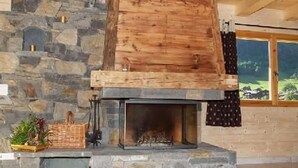 A stone fireplace with a wooden mantel, a basket, and a plant on the mantel. - Chalet, wifi, 100m from ski slopes, hammam, terrace, balcony, fireplace or stove, parking, tv (Le Grand-Bornand)