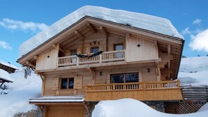 A wooden chalet with a balcony, surrounded by snow. - Chalet, wifi, 100m from ski slopes, hammam, terrace, balcony, fireplace or stove, parking, tv (Le Grand-Bornand)