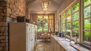 A kitchen with stone walls, a wooden counter, and a window with a view of greenery. - Wisteria Holiday Home (Lonato)