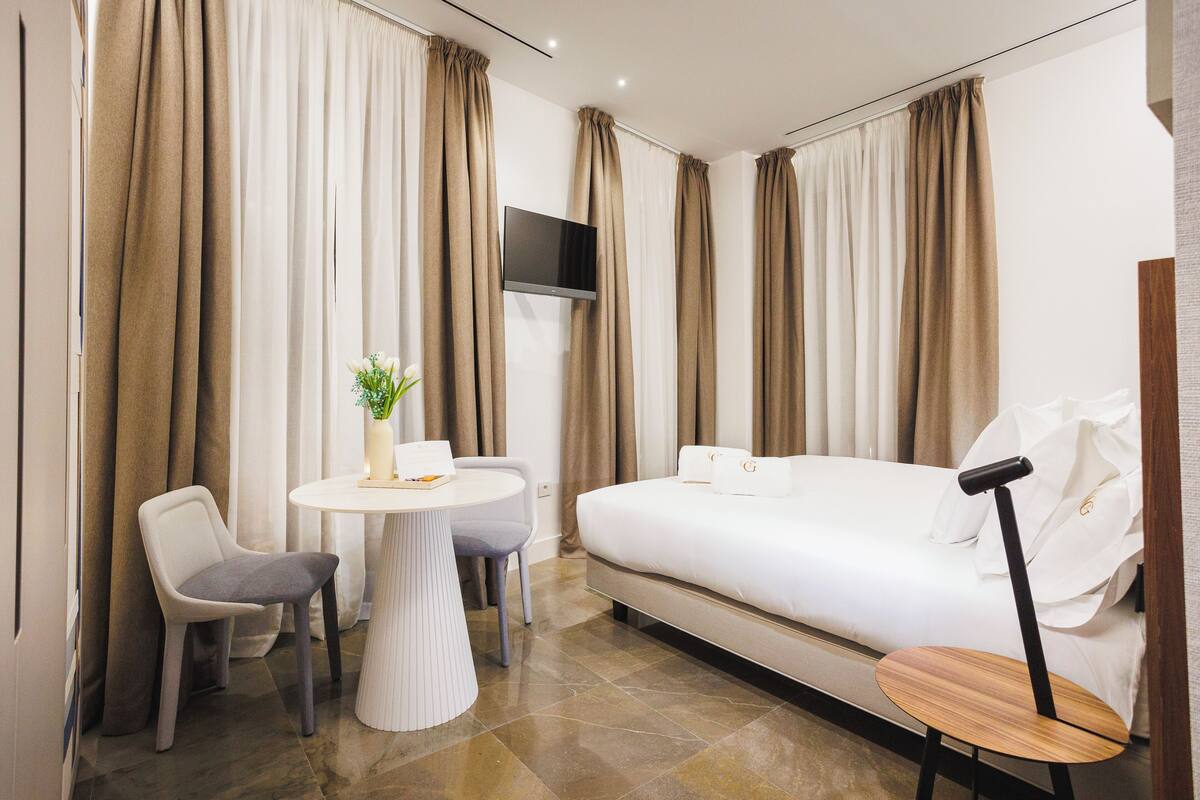 Una habitación de hotel con cama, escritorio, silla y televisor.