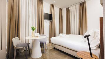 Una habitación de hotel con cama, escritorio, silla y televisor.