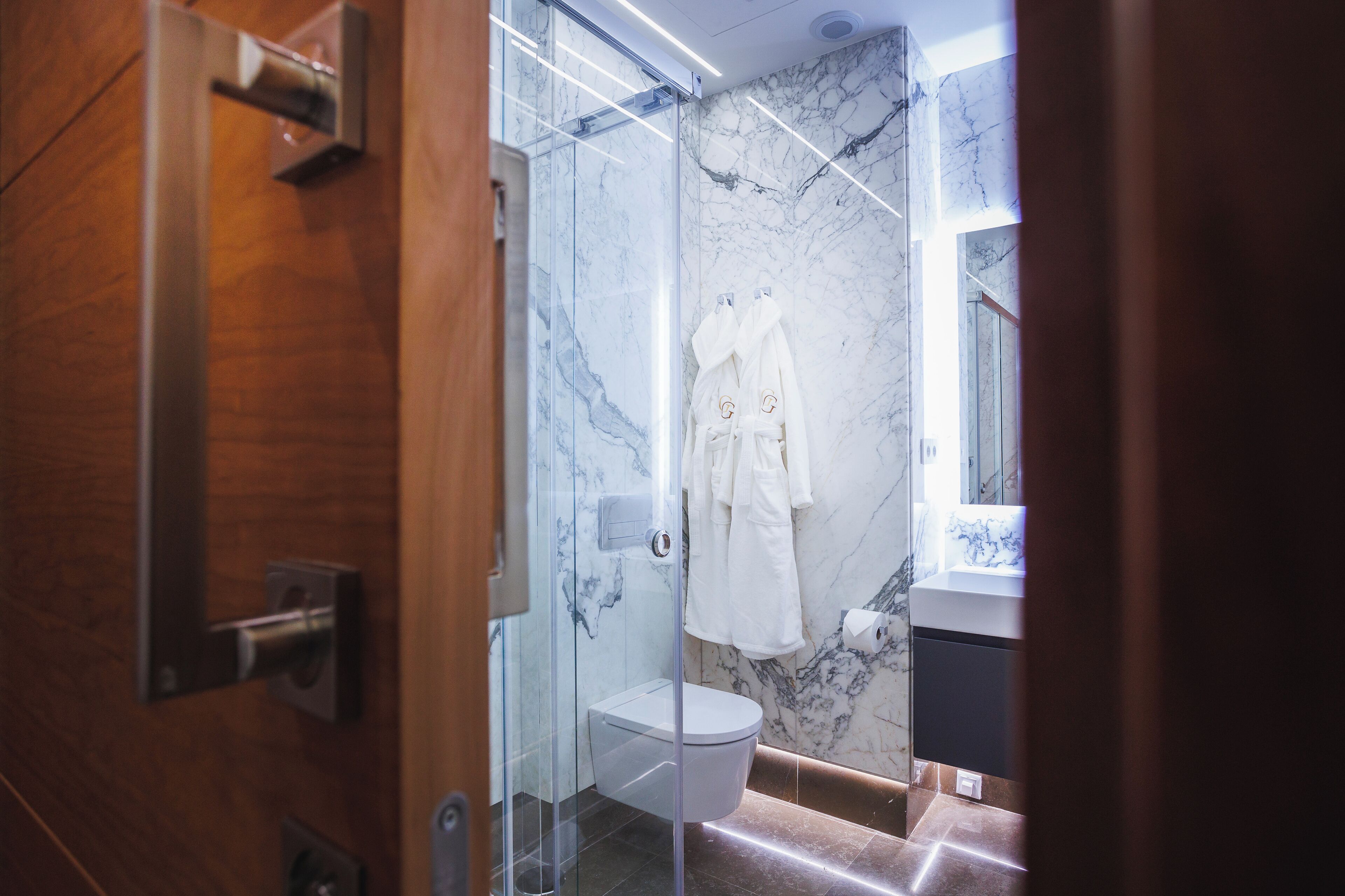 Ein modernes Badezimmer mit einer Duschkabine aus Glas, Marmorwänden und einer weißen Toilette.