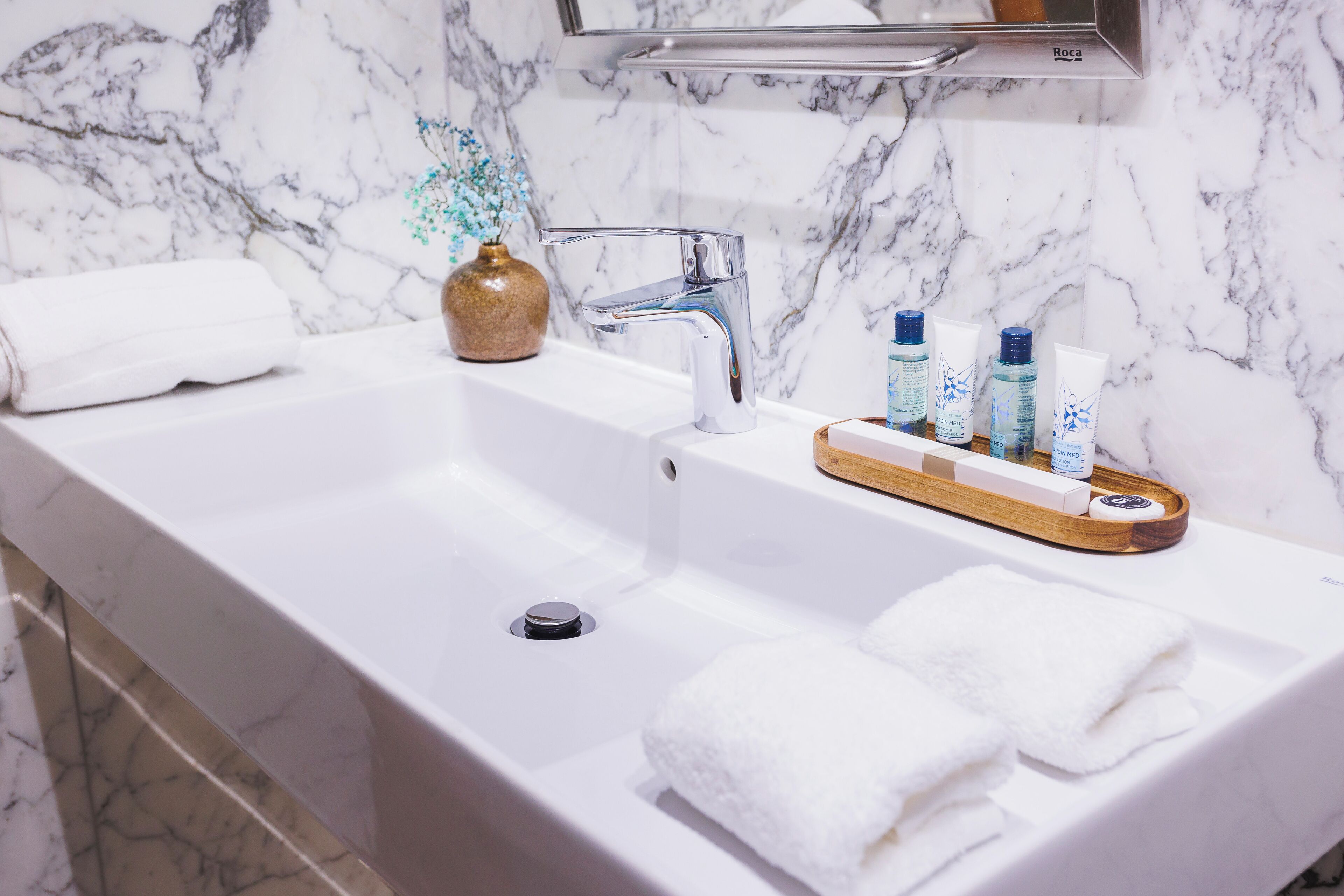 A bathroom with a marble sink, a mirror, and toiletries on the counter.