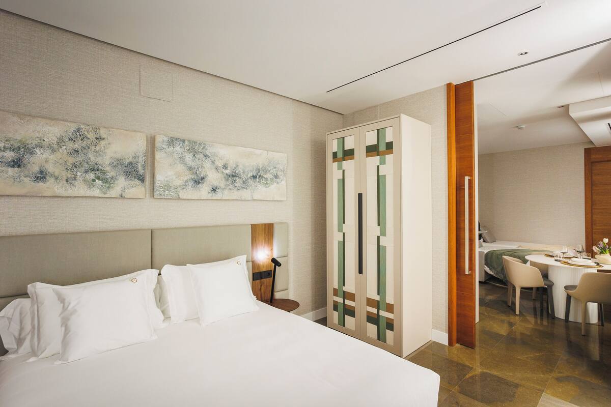 Habitación de hotel con una cama grande, un escritorio y sillas, y obras de arte en la pared.